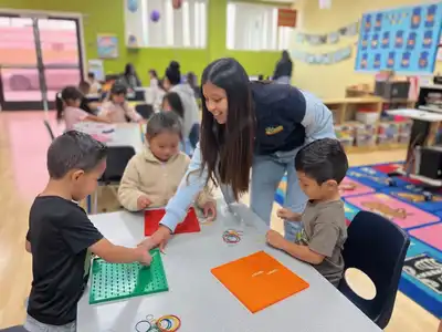 4-year-old Pre-K children at Kids Adventure Learning Center doing a hands-on curriculum activity with a teacher preparing for kindergarten