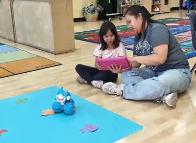 Preschool educator providing individualized attention and hands-on learning support to young children in a caring classroom environment