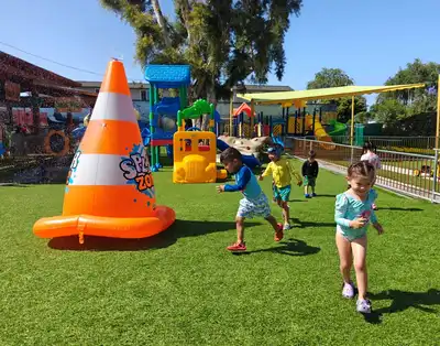 Preschool children playing and cooling off with sprinklers and water slides during summer at Kids Adventure Learning Center